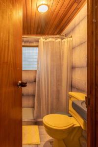 uma casa de banho com um WC amarelo e um chuveiro em Cabaña duplex el Sosiego. em El Tigre