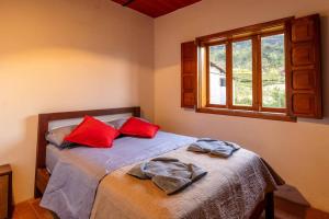a bedroom with a bed with red pillows and a window at Cabaña duplex el Sosiego. in El Tigre