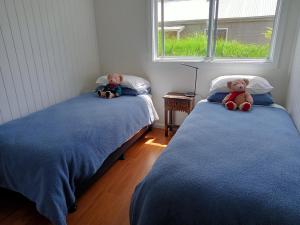 two beds with teddy bears sitting on them in a bedroom at The Gardener's Cottage on Warrentinna in Branxholm