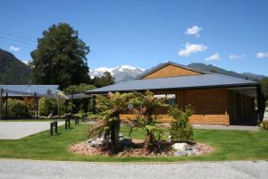 a building with a palm tree in front of it at Westwood Lodge in Franz Josef
