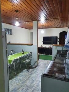 a living room with a green table and a tv at Recanto do sossego in São Bento do Sapucaí