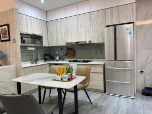 eine Küche mit einem Tisch und einem Kühlschrank in der Unterkunft Triple One Entire Home 慶東111私人招待所 包棟民宿 in Tainan