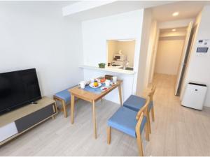 sala de estar con mesa, sillas y TV en Eslead Hotel Osaka Tsuruhashi - Vacation STAY 77560v en Osaka