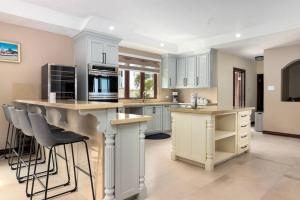 a kitchen with white cabinets and a island with bar stools at Oceanfront Luxe Villa In St Mary Fully Staffed in St Mary