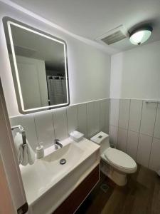 a bathroom with a sink and a toilet and a mirror at Jemet - Moderno Apartamento Doble in Guatemala