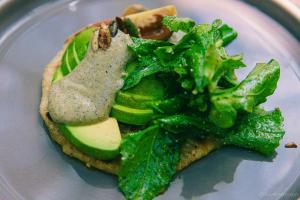 a plate with a sandwich with broccoli and avocado at Kapok Bacalar - Plant Based Hotel in Buenavista