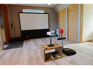 Qiao No,105 - Vacation STAY 75661v في Hokota: غرفة بها شاشة بيضاء وطاولة بها مصباح