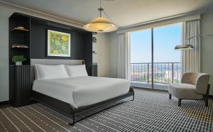 a bedroom with a large white bed and a chair at Pendry Newport Beach in Newport Beach
