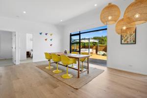 een eetkamer met een tafel en gele stoelen bij House Naomi - Martinborough Holiday Home in Martinborough 