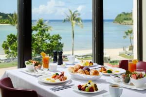 stół z jedzeniem i widokiem na plażę w obiekcie Hoshino Resorts RISONARE Guam w Tamuning