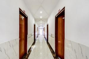 pasillo de un edificio con 2 puertas y suelo de mármol en OYO Flagship Hotel Capital Hill, en Rajgir