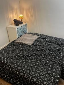 a bed with a black and white comforter in a room at Lilliputiens in Rouen