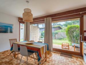 a dining room with a table and a large window at Maison 6 pers. à Mimizan, bord de courant, forêt et océan, 3 étoiles, tout confort, ménage inclus - FR-1-50-80 in Mimizan