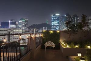 balcón con banco y vistas al perfil urbano por la noche en Seoul Station Joey N Ray house en Seúl