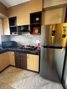 a kitchen with a stainless steel refrigerator and wooden cabinets at 3-BHK with pool & highway view. in Ghaziabad