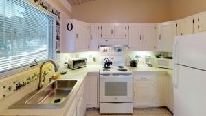 a white kitchen with a sink and a refrigerator at Silver Spring Chalet home in Pittsfield
