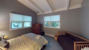 a bedroom with a bed and a couch and two windows at Silver Spring Chalet home in Pittsfield