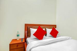 1 dormitorio con 2 camas con almohadas rojas y mesita de noche en OYO Yash Hotel, en Ghaziabad