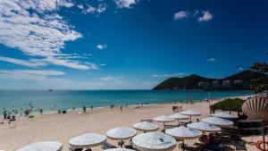a beach with umbrellas and people on the beach at Yolo Vacation Homestay in Sanya