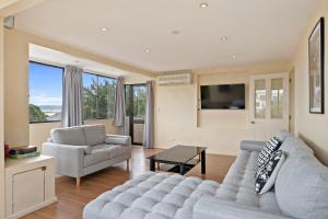 - un salon avec un canapé, des chaises et une télévision dans l'établissement Relax on Queens - Waikanae Beach Holiday Home, à Waikanae