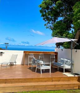 a wooden deck with chairs and an umbrella at Villa Moderne et Piscine Privée in Saint-Pierre