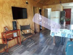 Habitación con mesa, sillas y TV. en Acogedora cabaña para disfrutar y descansar, en Olmué