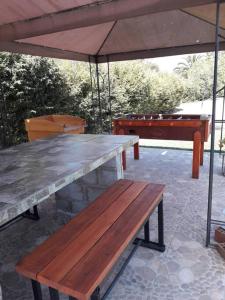 una mesa y bancos bajo una sombrilla en un patio en Acogedora cabaña para disfrutar y descansar, en Olmué