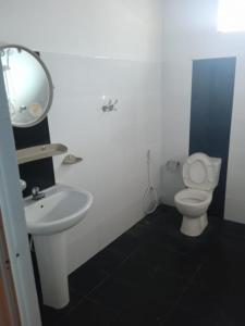 a bathroom with a toilet and a sink and a mirror at RS Holiday Residence in Ilukkumbura