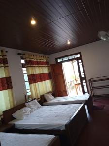 two beds in a room with two windows at RS Holiday Residence in Ilukkumbura