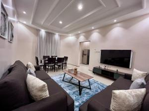 a living room with a couch and a tv and a table at شقق نسج المسكن دخول ذاتي شمال الرياض in Riyadh