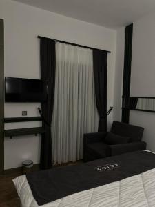 Gokceada Town的住宿－AGİOS HOTEL，一间卧室配有一张床、一张沙发和一台电视