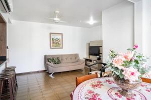 una sala de estar con una mesa con un jarrón de flores en Apartamento a 3 min apé da praia!, en Florianópolis