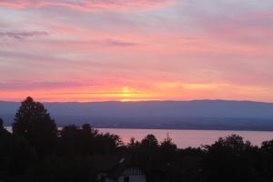 una puesta de sol sobre un cuerpo de agua con la puesta de sol en Le Chalet des 3 Ours en Neuvecelle