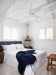 a white bedroom with a large bed with a white ceiling at Tamarind Beach Estate in Port Vila