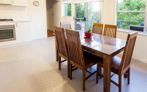 cocina y comedor con mesa de madera y sillas en Point Lonsdale Holiday Apartments, en Queenscliff