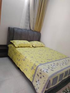 een bed met een gele sprei en 2 kussens bij Homestay Ijan in Cyberjaya