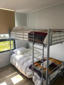 1 Schlafzimmer mit 2 Etagenbetten und einem Fenster in der Unterkunft Agradable depa en Llanquihue in Llanquihue