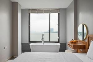 Schlafzimmer mit Badewanne und Fenster in der Unterkunft Lakeview Residence Hotel in Hanoi