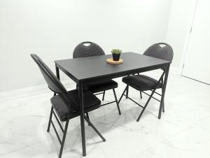 Newcastle的住宿－Urban Haven: 2BR/2BA+Office, Kitchen, Dining，一张带四把椅子的黑桌子和一株植物