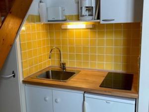 cocina con fregadero y pared de azulejos amarillos en Appartement Saint-Martin-de-Ré, 2 pièces, 4 personnes - FR-1-544-26, en Saint-Martin-de-Ré