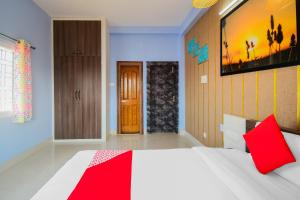 ein Schlafzimmer mit einem großen weißen Bett mit roten Kissen in der Unterkunft Flagship Sunshine Stay in Bhubaneshwar