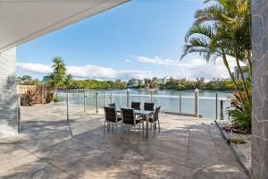 een patio met een tafel en stoelen naast een rivier bij CASSA CHEVRON ISLAND- Luxury Waterfront House in Gold Coast