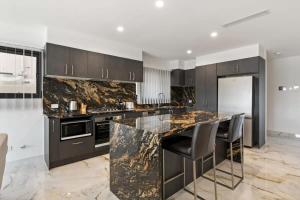 een keuken met een marmeren aanrecht en zwarte kasten bij CASSA CHEVRON ISLAND- Luxury Waterfront House in Gold Coast