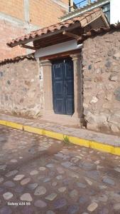 a stone building with a blue door on a street at Andahuaylillas Quedate Aqui in Andalmailillas