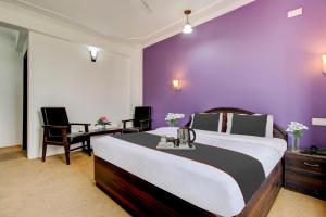 a bedroom with a large bed with a purple wall at Capital O Yasmin Resort in Baghwānpur