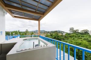 un balcón con bañera de hidromasaje al aire libre y barandilla azul en Costa Village Jacuzzi Bangsaray en Bang Sare