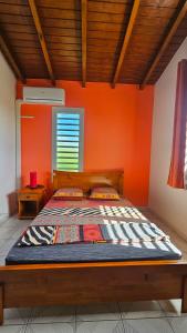 Cama en habitación con pared de color naranja en Maison (Vu sur le Lagon) en Le Gosier