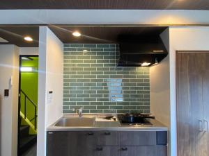 a kitchen with a sink and a green tile wall at Kobe Motomachi Roji Building - Vacation STAY 16197 in Kobe