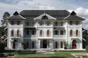 a large white house with a black roof at Sela Chiangmai in Chiang Mai