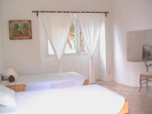 Vila Nova SintraにあるSol na Baiaの白い部屋で、ベッド2台、窓が備わります。